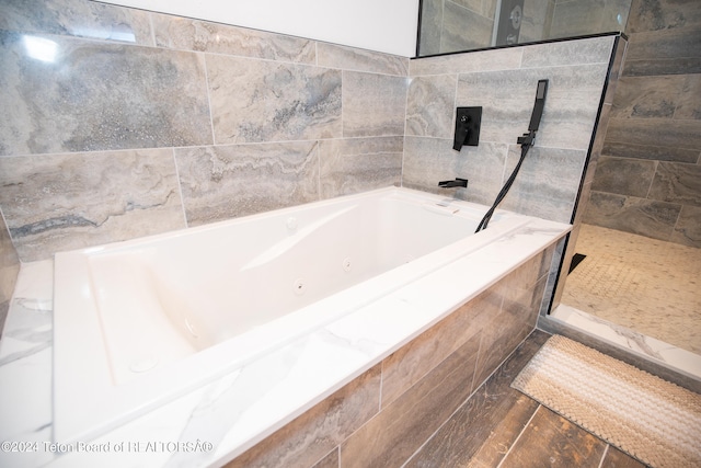 bathroom with shower with separate bathtub and tile walls