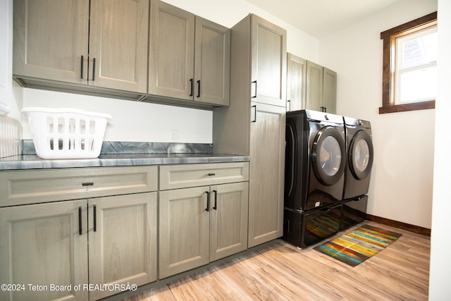 clothes washing area featuring washer and clothes dryer, cabinets, and light hardwood / wood-style flooring