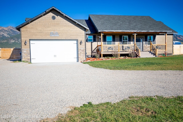 view of front facade featuring a front lawn, a mountain view, covered porch, and a garage