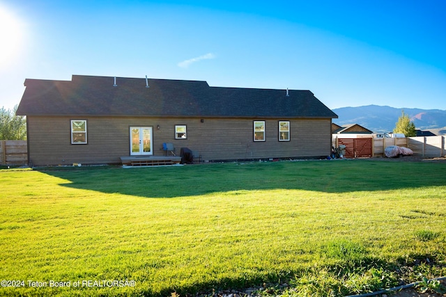 rear view of house with a lawn and a mountain view