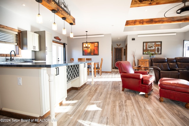 kitchen featuring a healthy amount of sunlight, light hardwood / wood-style floors, pendant lighting, and white cabinets