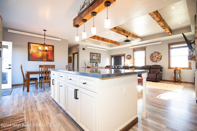 kitchen featuring light hardwood / wood-style floors, white cabinetry, pendant lighting, beam ceiling, and ceiling fan