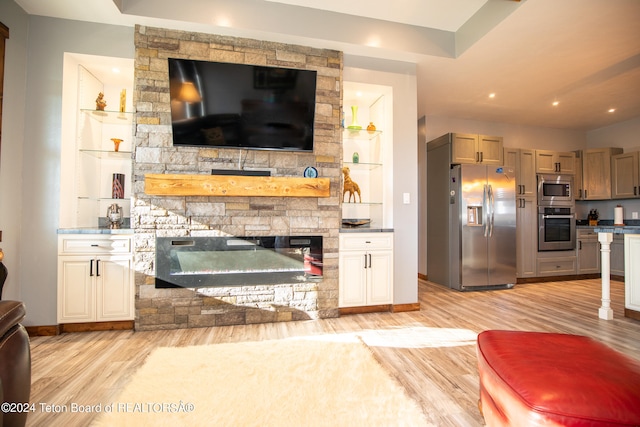 living room with light wood-type flooring, built in shelves, and a fireplace