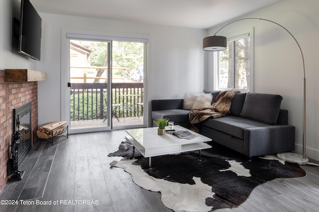 living area with plenty of natural light, a brick fireplace, and hardwood / wood-style flooring
