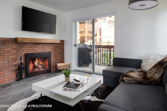 living room with a brick fireplace and hardwood / wood-style flooring