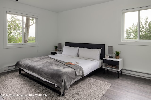 bedroom with baseboard heating and hardwood / wood-style floors