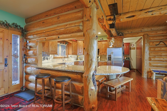 4120 W 9500 N, Tetonia, ID 83452 - kitchen with dark hardwood / wood-style floors, kitchen peninsula, stainless steel refrigerator with ice dispenser, log walls, and tasteful backsplash