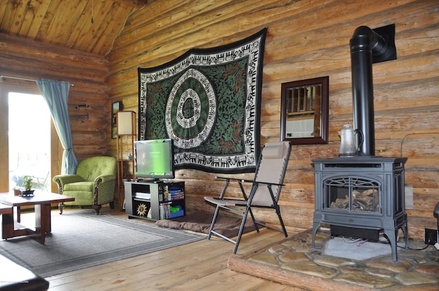 living room featuring high vaulted ceiling, a wood stove, and hardwood / wood-style flooring