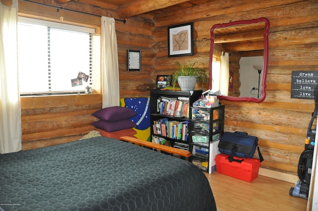 bedroom featuring beamed ceiling, rustic walls, and hardwood / wood-style flooring