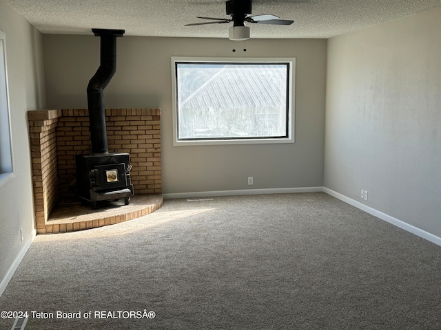 unfurnished living room with carpet floors, a textured ceiling, and a wood stove