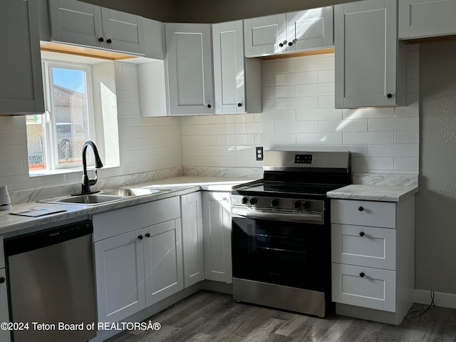 kitchen with tasteful backsplash, sink, white cabinets, appliances with stainless steel finishes, and dark hardwood / wood-style flooring