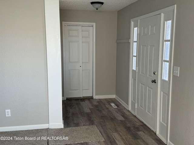 foyer with a textured ceiling and dark wood-type flooring