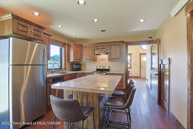 kitchen featuring a kitchen island, stainless steel appliances, dark wood-type flooring, sink, and a kitchen breakfast bar