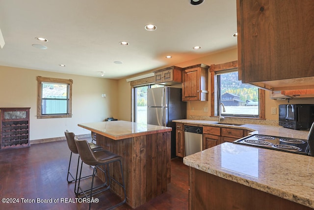 kitchen with a center island, dark hardwood / wood-style floors, sink, appliances with stainless steel finishes, and a kitchen breakfast bar