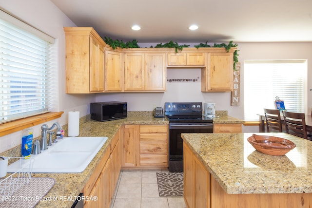 kitchen featuring light tile patterned flooring, black appliances, sink, and light stone counters