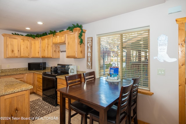 kitchen featuring light stone counters, black appliances, light brown cabinets, and light tile patterned floors