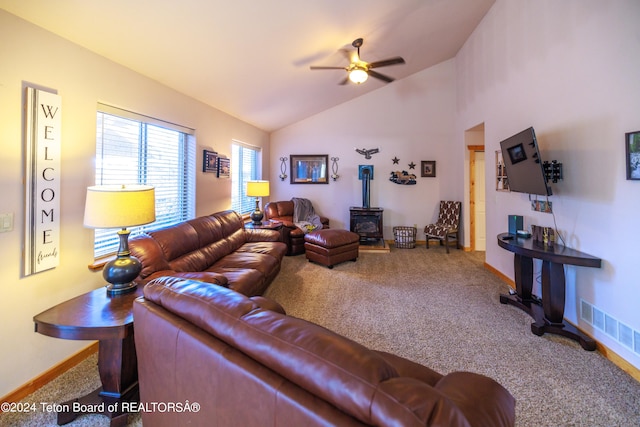 carpeted living room with a wood stove, lofted ceiling, and ceiling fan