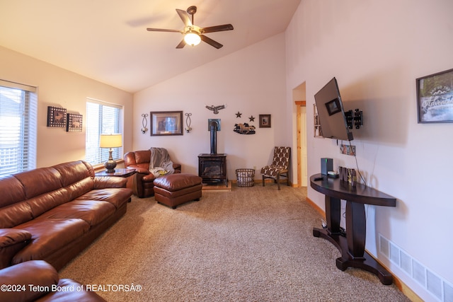 living room with ceiling fan, carpet flooring, a wood stove, and high vaulted ceiling