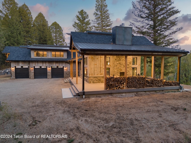 back house at dusk with a garage and covered porch