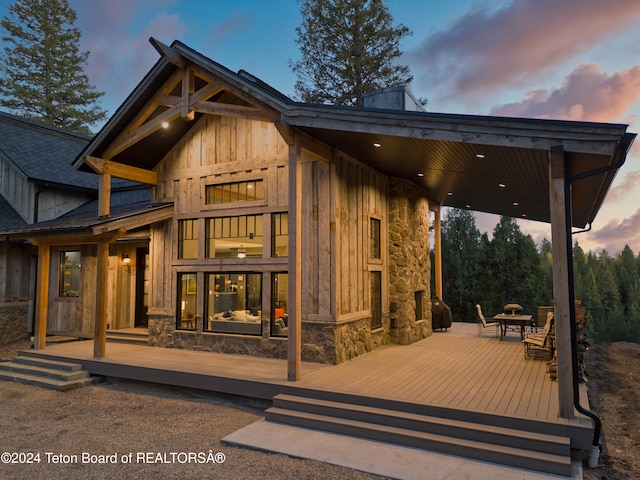 back house at dusk featuring a deck