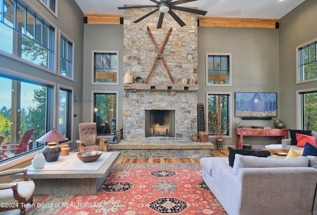 living room featuring a high ceiling, a fireplace, ceiling fan, and beam ceiling