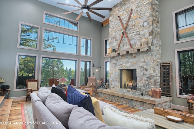 living room with a towering ceiling, a fireplace, hardwood / wood-style flooring, and ceiling fan