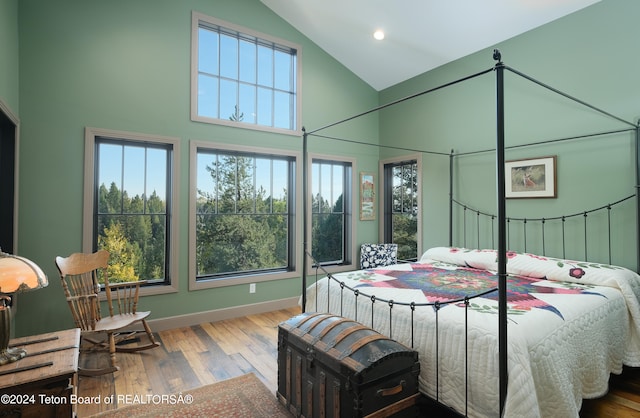 bedroom featuring high vaulted ceiling and light hardwood / wood-style flooring