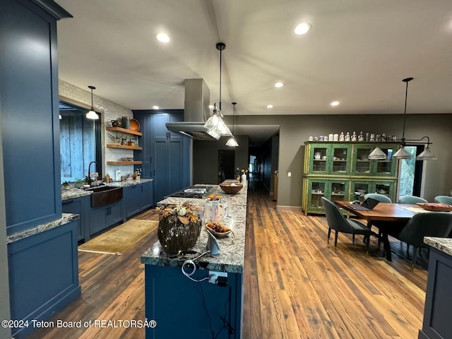 kitchen featuring pendant lighting, island exhaust hood, blue cabinetry, sink, and dark hardwood / wood-style floors