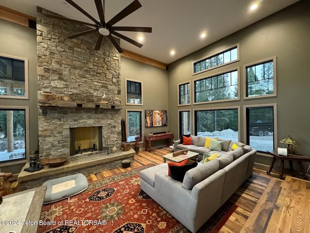 living room featuring ceiling fan, wood-type flooring, pool table, a fireplace, and a towering ceiling