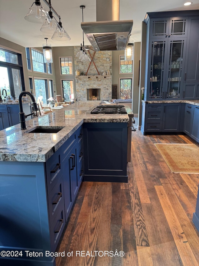 kitchen with extractor fan, stainless steel gas cooktop, blue cabinets, dark hardwood / wood-style flooring, and sink