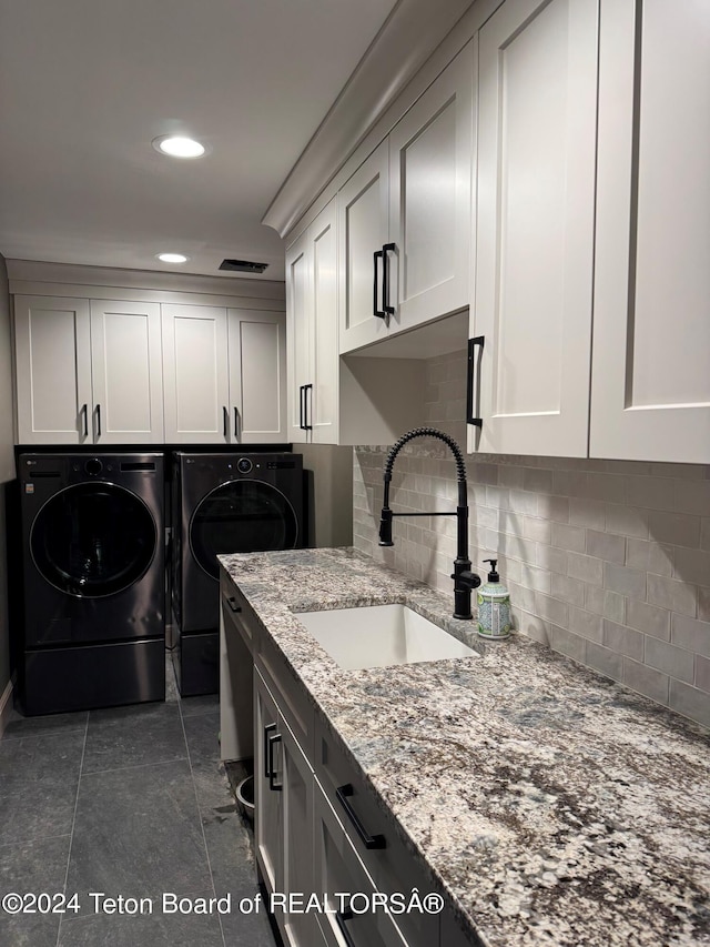 washroom with dark tile patterned floors, cabinets, sink, and washer and dryer