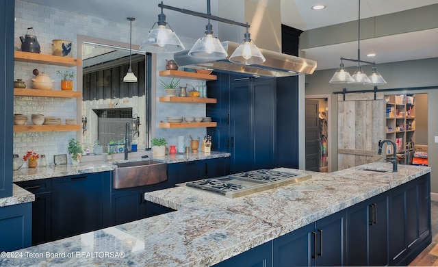 kitchen featuring tasteful backsplash, sink, hanging light fixtures, a barn door, and blue cabinets