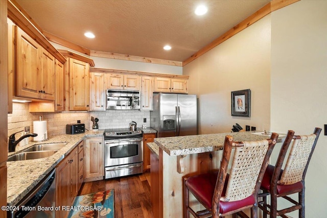 kitchen with a sink, decorative backsplash, dark wood finished floors, appliances with stainless steel finishes, and light stone countertops