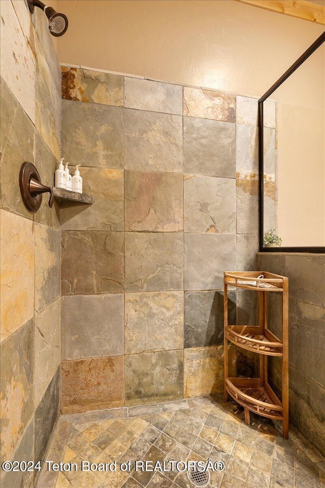 bathroom with stone finish floor and a tile shower