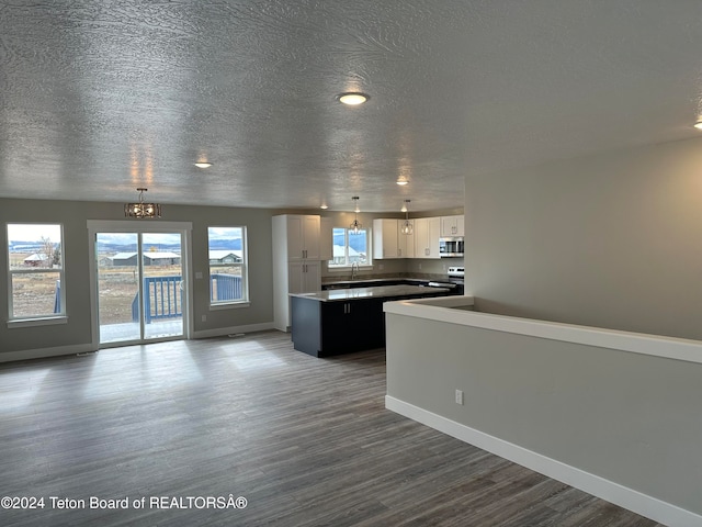 kitchen with pendant lighting, white cabinets, hardwood / wood-style flooring, a center island, and stainless steel appliances