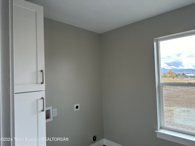 washroom with hookup for a washing machine, a textured ceiling, hookup for an electric dryer, and a healthy amount of sunlight