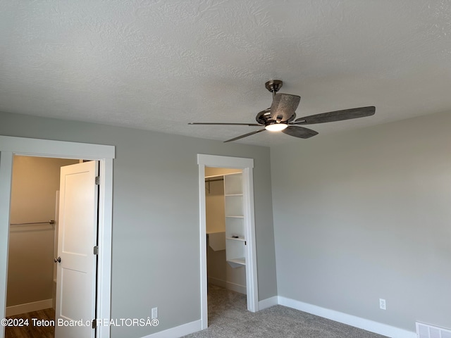 unfurnished bedroom featuring a walk in closet, a closet, and ceiling fan