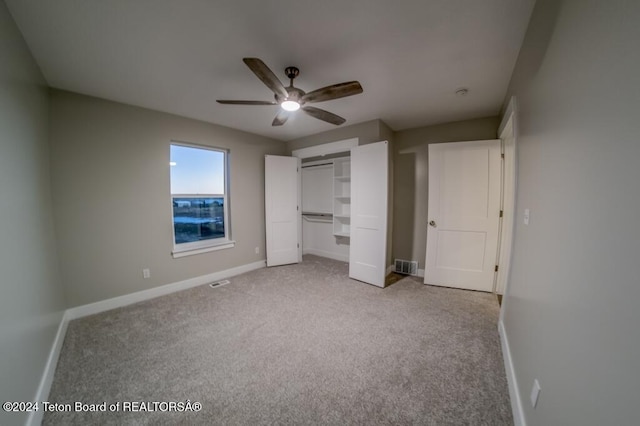 unfurnished bedroom with light colored carpet, ceiling fan, and a closet