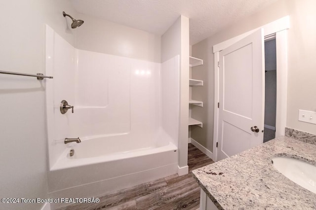 bathroom featuring vanity, bathtub / shower combination, hardwood / wood-style floors, and a textured ceiling