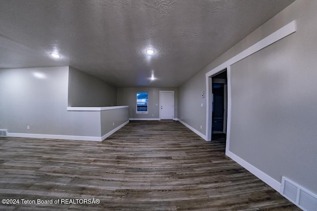 unfurnished living room with dark hardwood / wood-style flooring and a textured ceiling