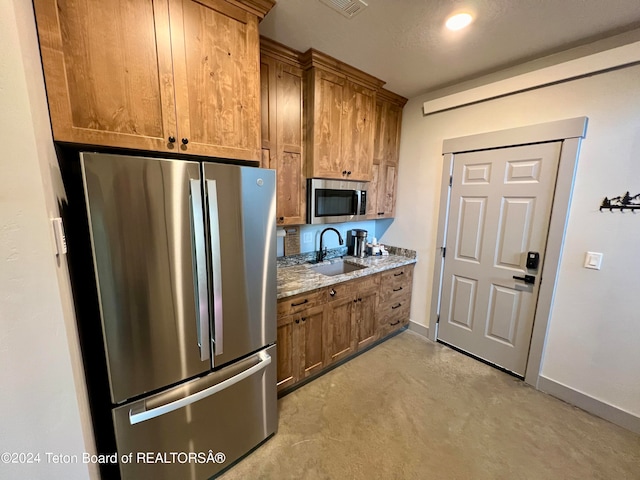 kitchen featuring light stone counters, sink, a textured ceiling, stainless steel appliances, and light carpet