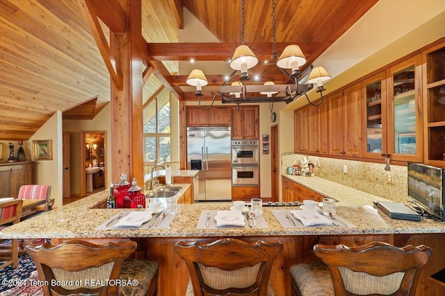 kitchen with pendant lighting, sink, kitchen peninsula, appliances with stainless steel finishes, and a kitchen bar