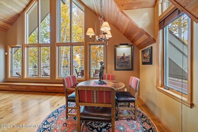 dining area with a healthy amount of sunlight, vaulted ceiling, hardwood / wood-style floors, and an inviting chandelier