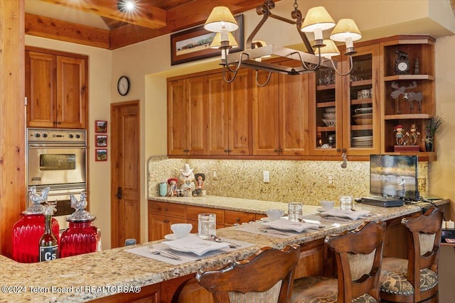 kitchen with light stone counters, decorative backsplash, a notable chandelier, hanging light fixtures, and beam ceiling