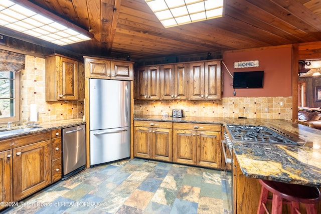 65 Bald Mountain Rd, Dubois, WY 82513 - kitchen with appliances with stainless steel finishes, wood ceiling, brown cabinets, tasteful backsplash, and stone finish flooring