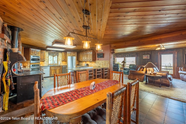 dining space featuring wood ceiling, wood walls, sink, dark tile patterned floors, and a wood stove