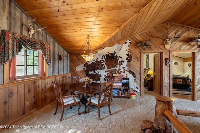 dining space featuring wooden walls, vaulted ceiling, wooden ceiling, and light colored carpet