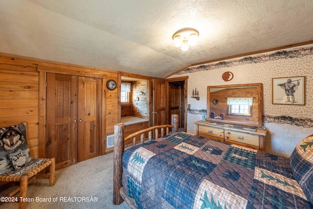 bedroom with light colored carpet, wooden walls, lofted ceiling, and a textured ceiling