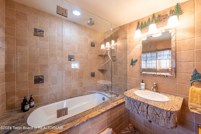 bathroom with vanity, tile walls, and tiled shower / bath