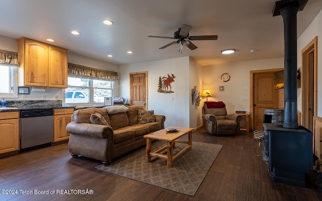 living room featuring ceiling fan, dark hardwood / wood-style flooring, and a wood stove